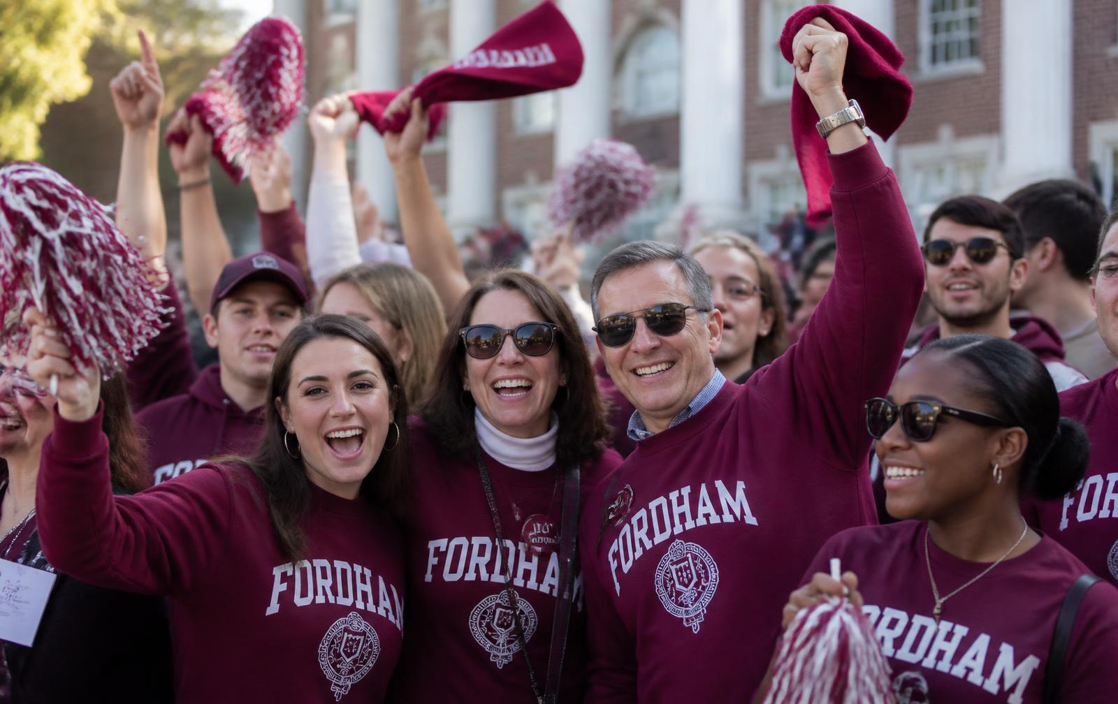 Alumni and students in branded homecoming apparel celebrating at a campus tailgate